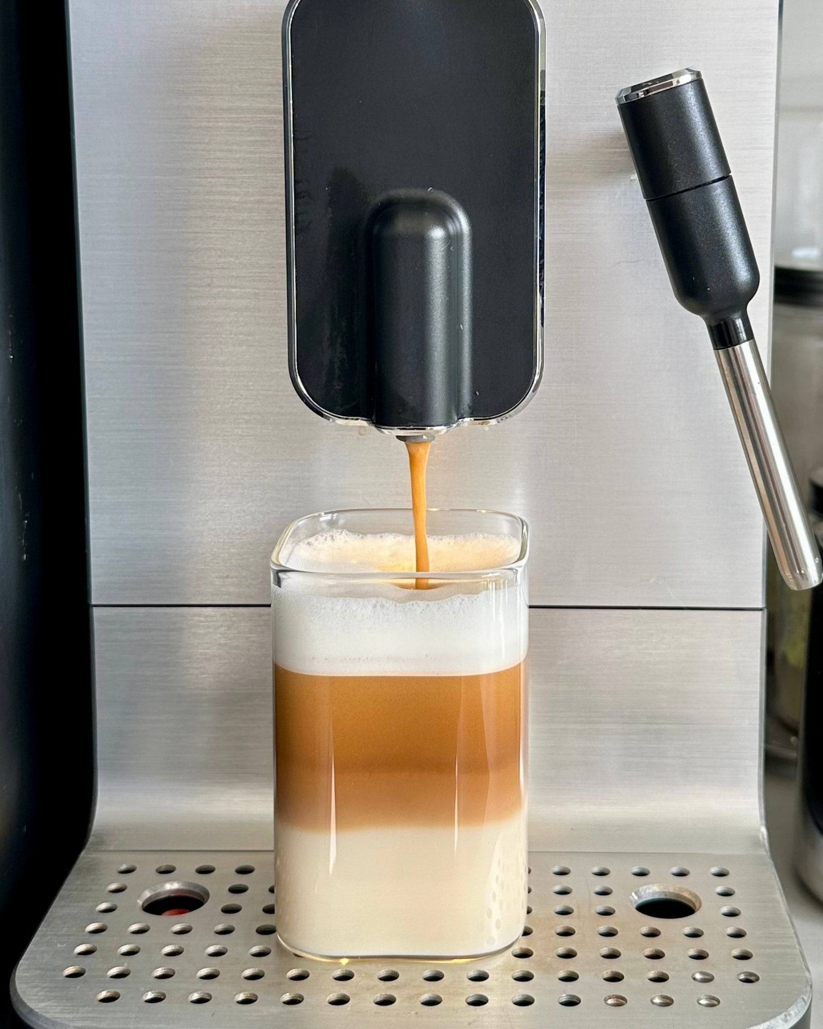 Smeg kaffemaskine laver latte macchiato i et lille Olivia firkantet drikkeglas i minimalistisk design