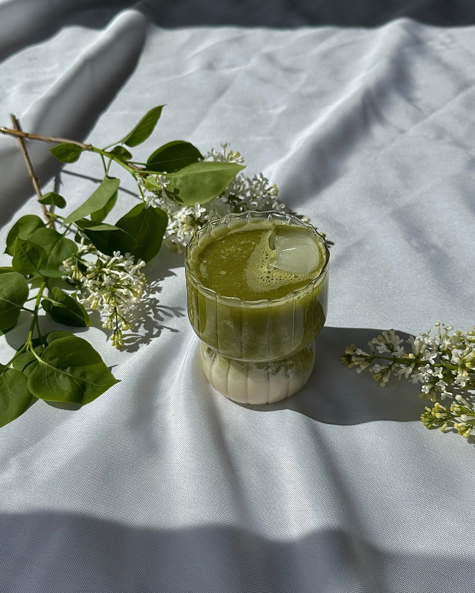 Matcha islatte serveret i Harper drikkeglas i riflet glasdesign på bord med blomster