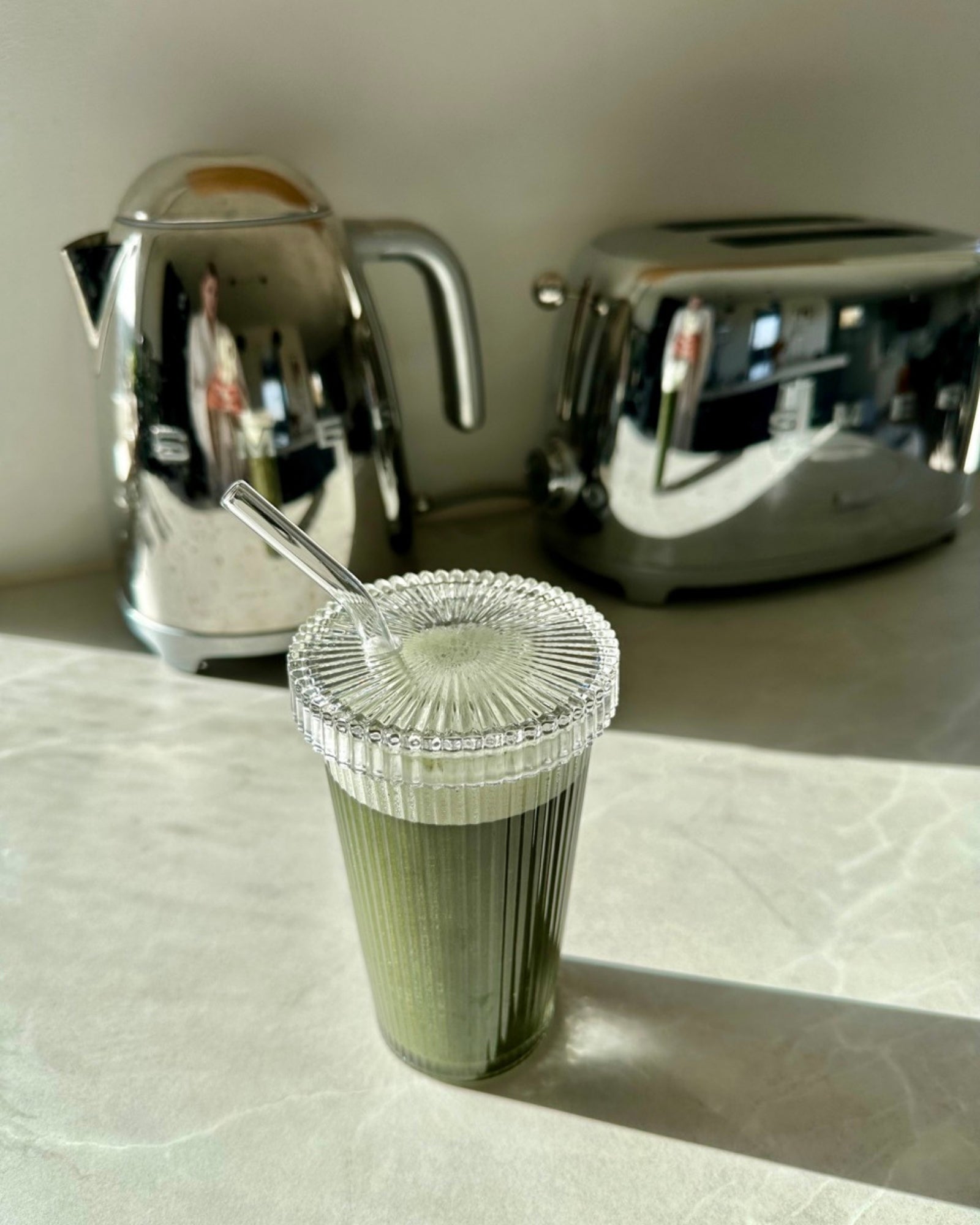 Matcha islatte serveret i en Emily riflet to go drikkeglas i glasdesign med sugerør 